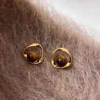 Goldene gewellte Ohrringe und Perlen in Tigeraugen-Optik