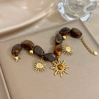 Bracelet bohème avec galets et pendentifs soleils effet oeil de tigre