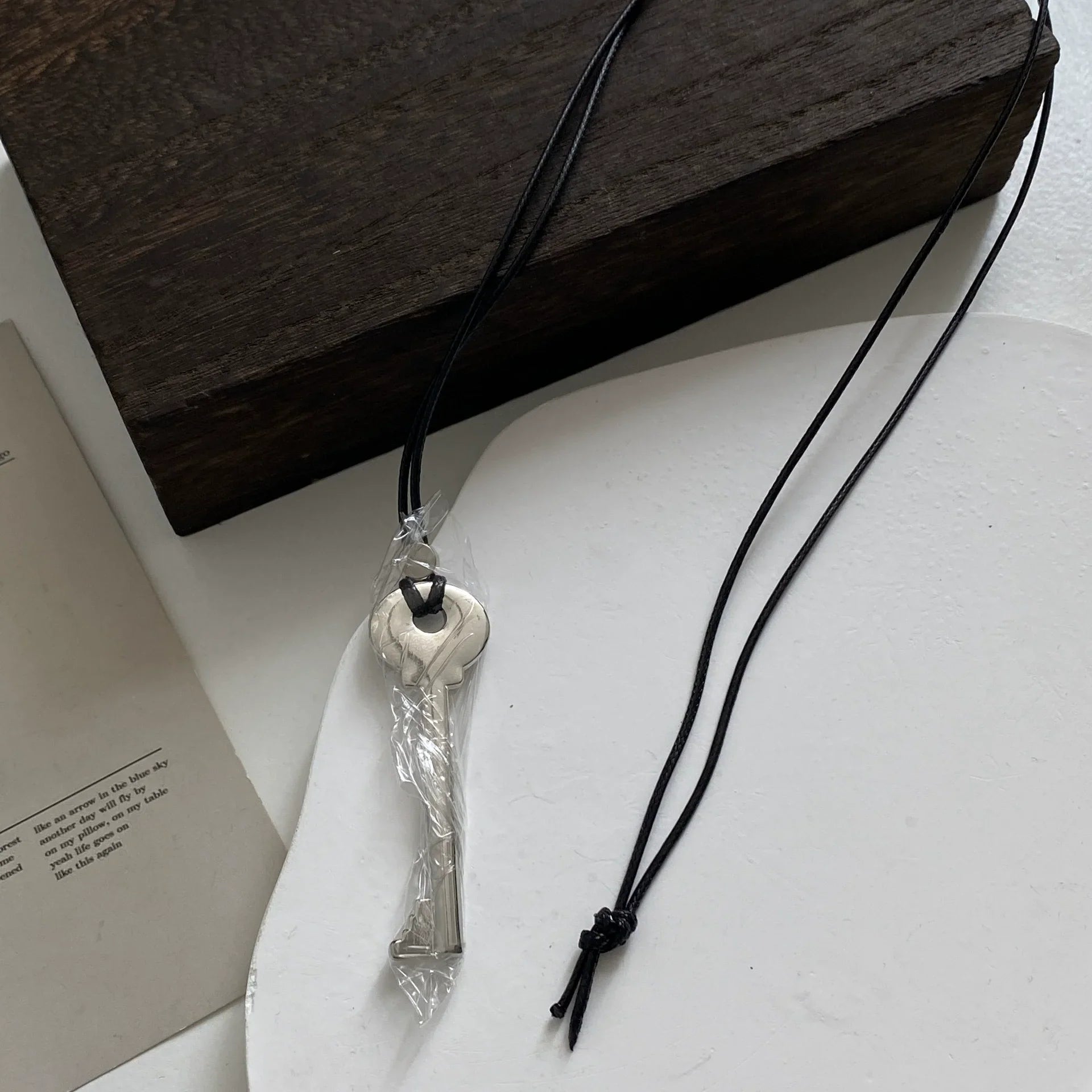 Lange Kette aus Kordel mit glänzend silbernem Schlüsselanhänger
